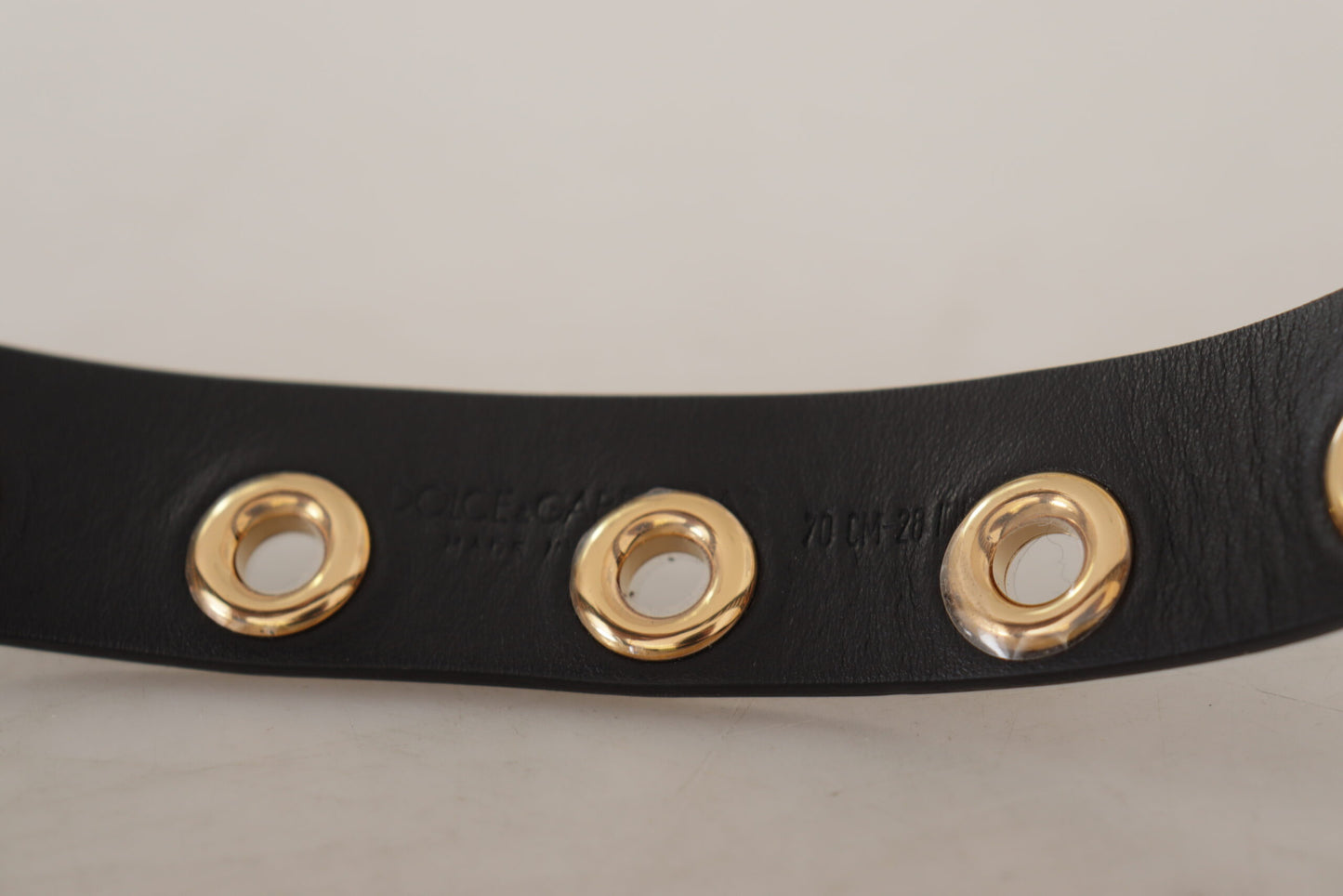 Cinturón de cuero negro con ojales y hebilla de metal en tono plateado
